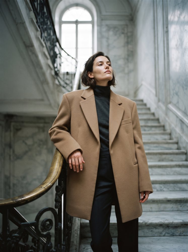 بورتريه أزياء من Nano Banana 2 لامرأة بمعطف جملي على سلم حجري